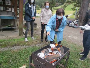 火傷に注意しながらホイルに包んだりんごを炭火へ